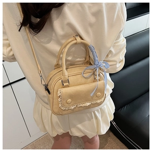 Close-up of cream mini pillow bag featuring lace pocket and ribbon bow on model