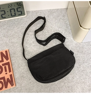 Gros plan détaillé d'un sac bandoulière noir en nylon en forme de croissant avec étiquette