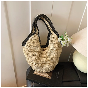 Detail of a woven straw hobo bag with black contrast trim and daisy flower decoration