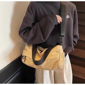 Detail of yellow canvas crossbody bag featuring side drawstring pocket and wide nylon strap