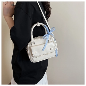 Detail of off-white PU leather mini bag with blue checkered silk ribbon and metallic buckle
