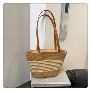 Detail view of handmade straw tote bag with brown leather straps and striped woven texture