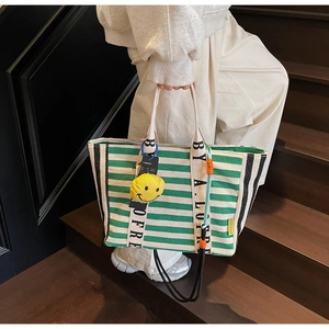 Detailed shot of large striped canvas tote bag with yellow smiley face charm on stairs