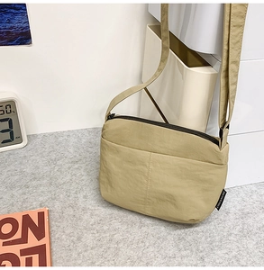 Détail du sac bandoulière en nylon kaki avec fermeture éclair noire et étiquette latérale