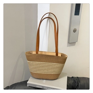 Detailed view of woven straw bucket bag with white gradient stripes and leather handles