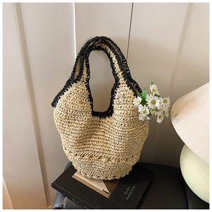 Detail of hobo straw shoulder bag with black crochet trim on vintage book background