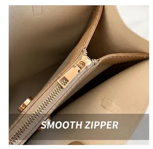 Close-up of smooth gold metal zipper and fine leather texture of the beige tote bag