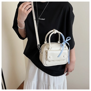 Detail of a chic cream-white crossbody bag featuring delicate lace trim and blue plaid ribbon