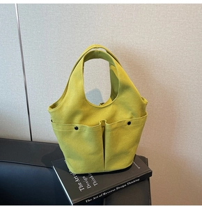 Detail of green canvas tote bag with dual front pockets and durable integrated handles
