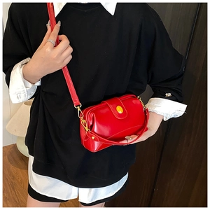 Détail d'un petit sac bandoulière rouge avec fermoir doré vintage et bandoulière cuir