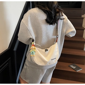 Minimalist white canvas half-moon crossbody bag with oomtao logo and cartoon charm detail