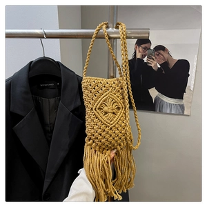 Gros plan du sac de téléphone en macramé jaune avec motifs losanges et longues franges