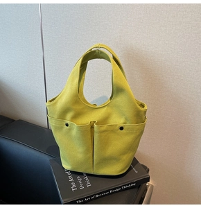 Detail showing mustard yellow canvas tote bag with double front pockets and metal rivets