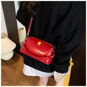 Détail d'un sac bandoulière vintage en cuir rouge avec un élégant fermoir doré en métal