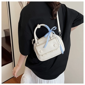 Chic mini crossbody pillow bag in beige leather with ribbon bow and lace detail on model