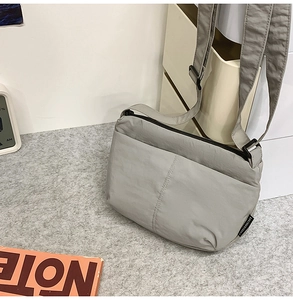 Gros plan sur un sac bandoulière en nylon gris avec poche zippée et sangle réglable