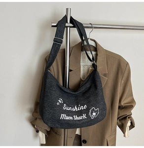 Détail du sac lune en toile gris foncé avec broderie blanche et bandoulière ajustable
