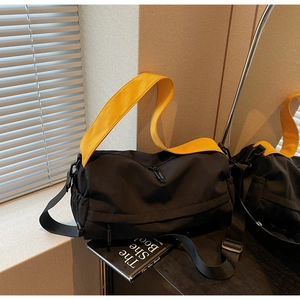 Detail of black nylon pillow bag with contrasting bright yellow handles and zip closure