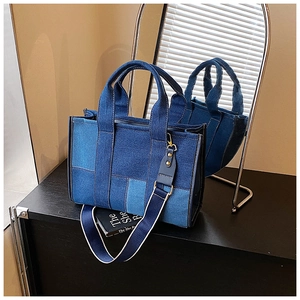 Detail of color-block denim tote bag featuring dual handles and adjustable shoulder strap