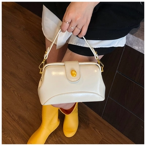 Mannequin tenant un sac rétro en cuir blanc brillant avec des boucles en métal doré chic