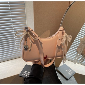 Dettaglio borsa hobo rosa con fiocco di perle, pendente a cuore e nastro in pizzo