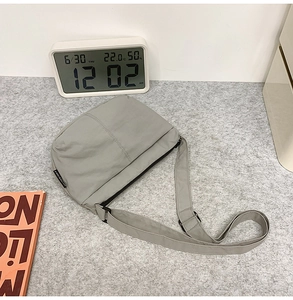 Gros plan sur un sac bandoulière gris minimaliste avec sangle réglable sur feutre