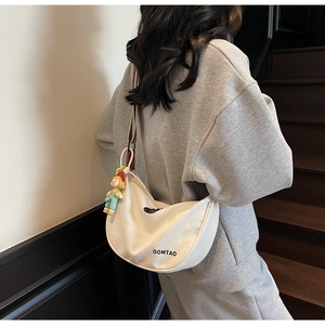 Off-white crescent crossbody bag with colorful striped strap and cartoon charm