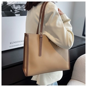 Detail of a dual-tone tote bag with adjustable shoulder strap on a professional model