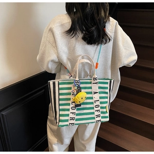 Close-up of green striped canvas tote with yellow smiley charm on wooden stairs