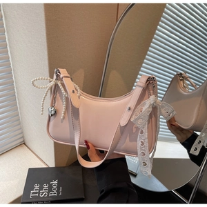 Dettaglio della borsa hobo in pelle rosa chiaro con fiocco di perle e nastro di pizzo