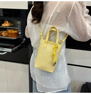Dettaglio della mini borsa tote gialla intrecciata con tracolla a nodi indossata