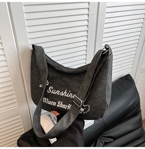 Détail du sac hobo en toile grise avec inscription blanche et bandoulière large