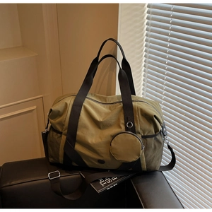 Details einer olivgrünen Reisetasche aus Nylon auf einem Ledersofa mit seitlichem Netzfach