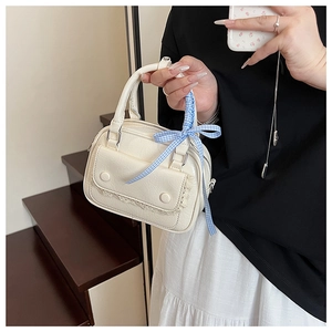 Detail of cream mini pillow bag with lace trim and blue checkered silk scarf on handle