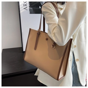Detail of a large tote bag featuring beige and brown patchwork with white contrast stitching