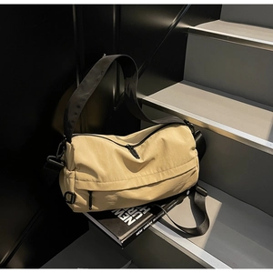 Detailed close-up of beige nylon crossbody bag with black adjustable strap and metal hardware
