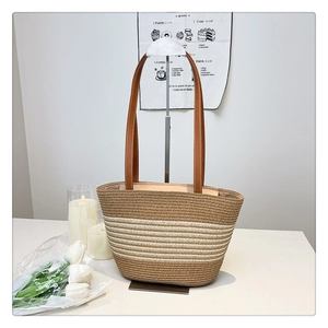 Detail of handwoven straw tote bag with brown leather straps in a cozy setting
