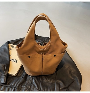 Detail of khaki canvas tote bag with utility pockets and metal buckle on leather jacket