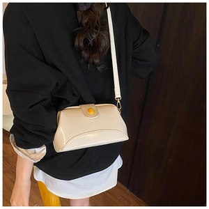 Détail d'un sac à main beige vintage avec fermeture à cadre métallique et bouton jaune