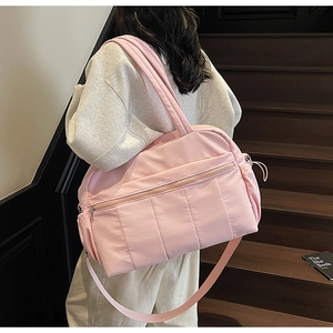 Quilted pink travel bag with detachable shoulder strap shown on a wooden staircase