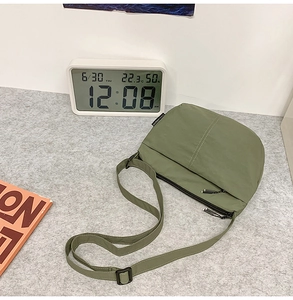 Détail du sac bandoulière en nylon vert armée avec sangle réglable sur tapis gris