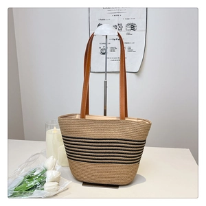 Detailed view of straw woven tote with black stripes and brown leather strap