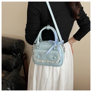 Detail of light blue PU leather handbag with lace trim and blue checkered ribbon bow