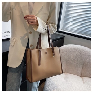 Detail view of khaki and brown color-blocking tote bag with vintage button and fine texture