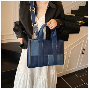 Detail of blue patchwork denim tote bag with adjustable strap and stitching accents