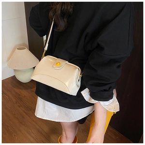 Détail d'un sac bandoulière vintage blanc crème avec fermoir doré porté à l'épaule