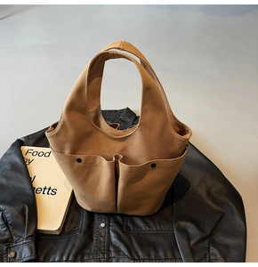 Close-up of khaki canvas tote bag with dual front pockets and black metallic buttons