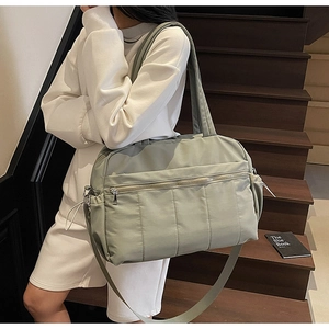 Close-up of sage green travel bag with drawstring side pockets and dual handles