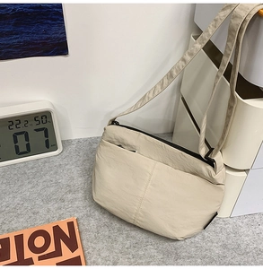 Détail du sac bandoulière en nylon beige avec tissu imperméable et fermeture éclair noire