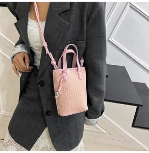 Dettaglio borsa a tracolla intrecciata rosa con ciondolo a elefante e manico sottile
